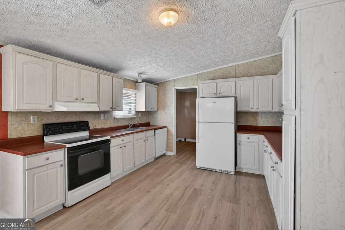 4156 Smiley Road Ludowici, GA 31316 - Photo 17 of 32 a kitchen with a white cabinets and wooden floor