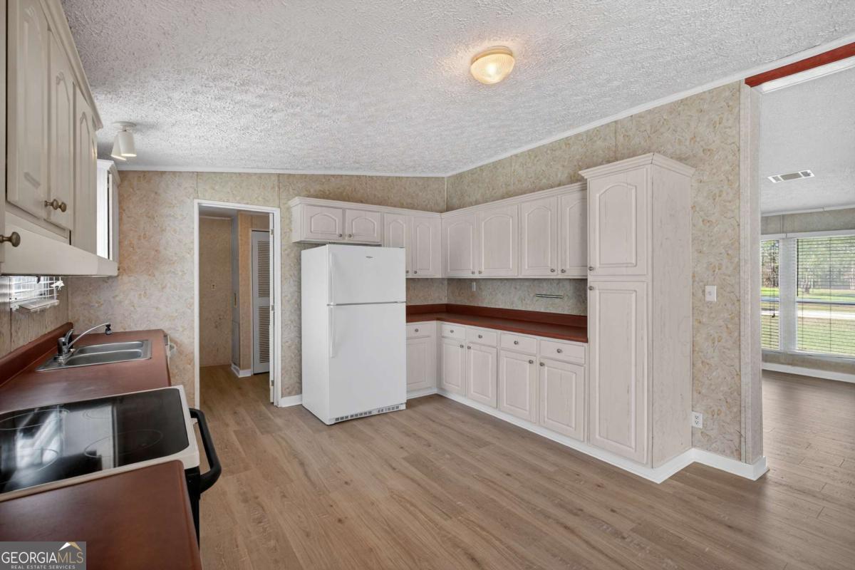 4156 Smiley Road Ludowici, GA 31316 - Photo 18 of 32 a kitchen with a refrigerator sink and cabinets