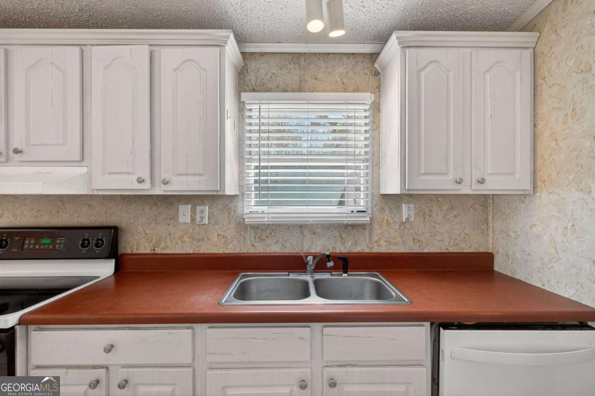 4156 Smiley Road Ludowici, GA 31316 - Photo 19 of 32 a kitchen with stainless steel appliances granite countertop a sink a stove and white cabinets