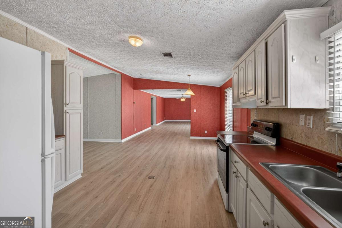 4156 Smiley Road Ludowici, GA 31316 - Photo 20 of 32 a kitchen with a sink a stove cabinets and wooden floor