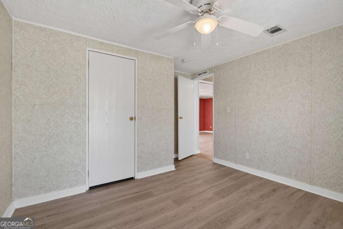 4156 Smiley Road Ludowici, GA 31316 - Photo 26 of 32 an empty room with wooden floor fan and windows