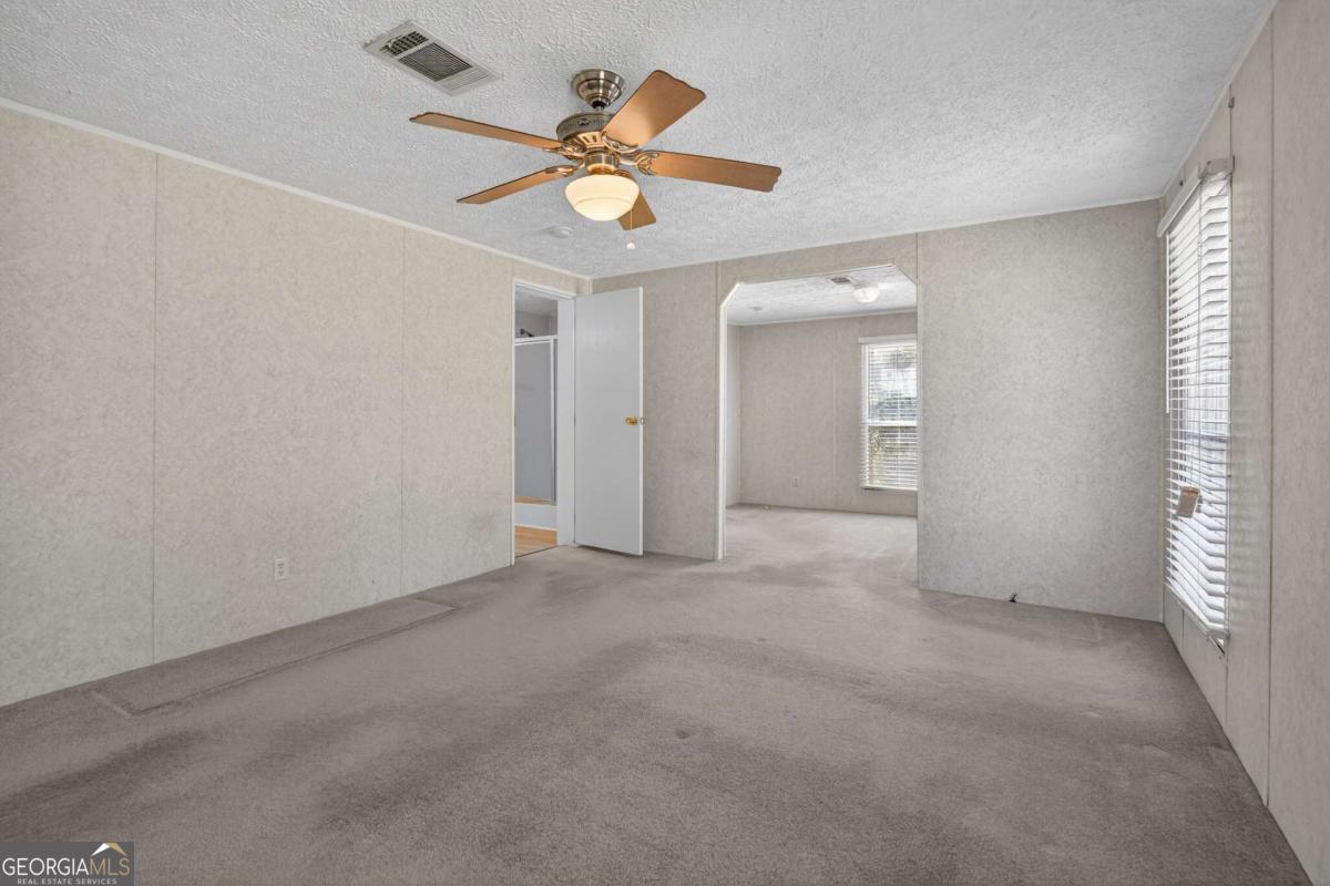 4156 Smiley Road Ludowici, GA 31316 - Photo 4 of 32 an empty room with a ceiling fan and a window