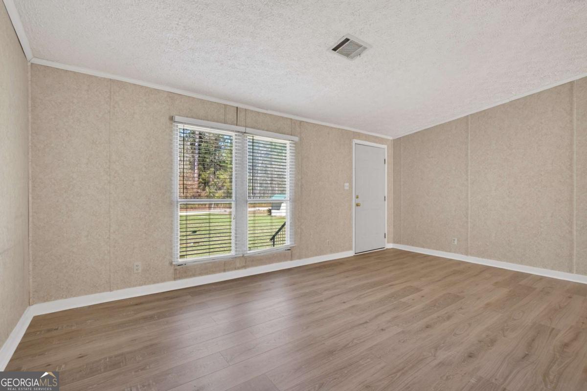 4156 Smiley Road Ludowici, GA 31316 - Photo 10 of 32 a view of an empty room with wooden floor and a window
