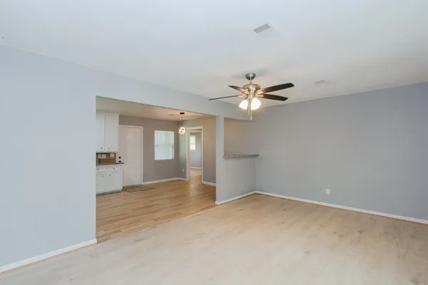 a view of an empty room with chandelier fan