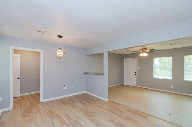 an empty room with wooden floor and windows