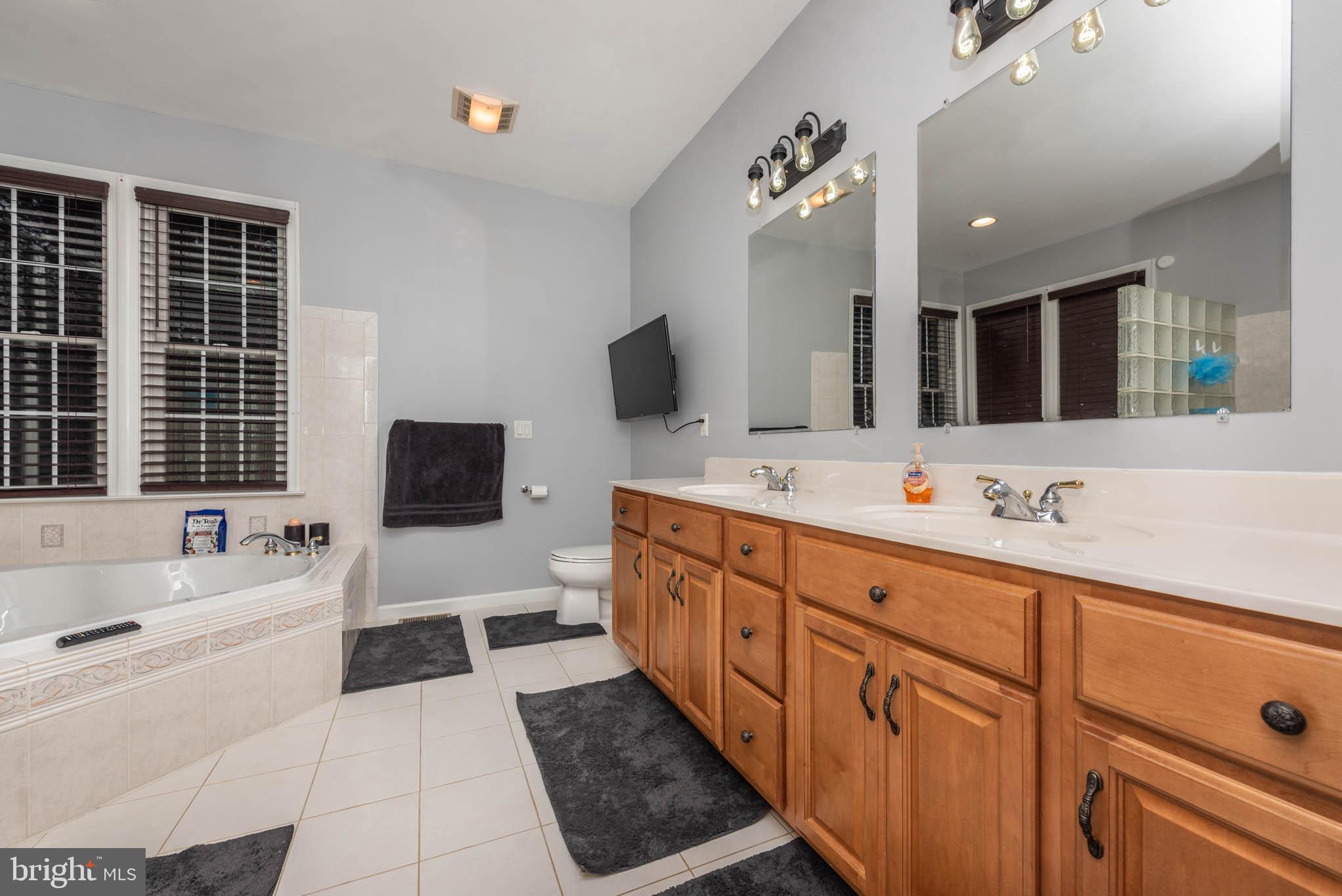 2623 Urey Road White Hall, MD 21161 - Photo 18 of 60 a spacious bathroom with double vanity a large mirror and a bathtub