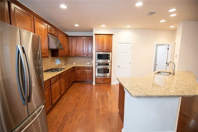 a kitchen with stainless steel appliances granite countertop a refrigerator a sink and a stove