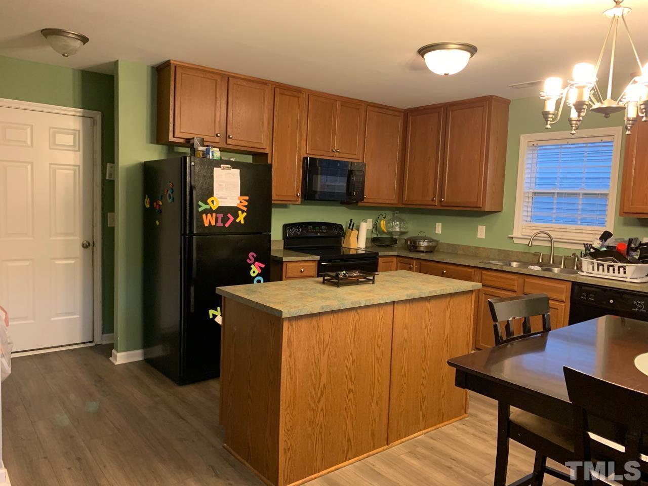 1422 Infinity Lane Raleigh, NC 27610 - Photo 8 of 16 a kitchen with a refrigerator a stove a sink and a microwave with wooden floor