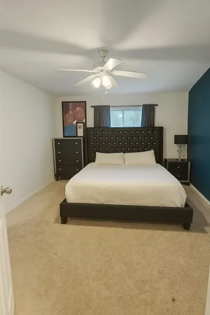 a large bed sitting in a room next to a lamp with kitchen and chandelier