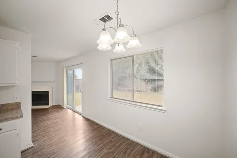 a view of an empty room with a kitchen and wooden floor