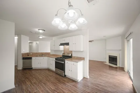 a kitchen with granite countertop a stove top oven a sink dishwasher and a refrigerator