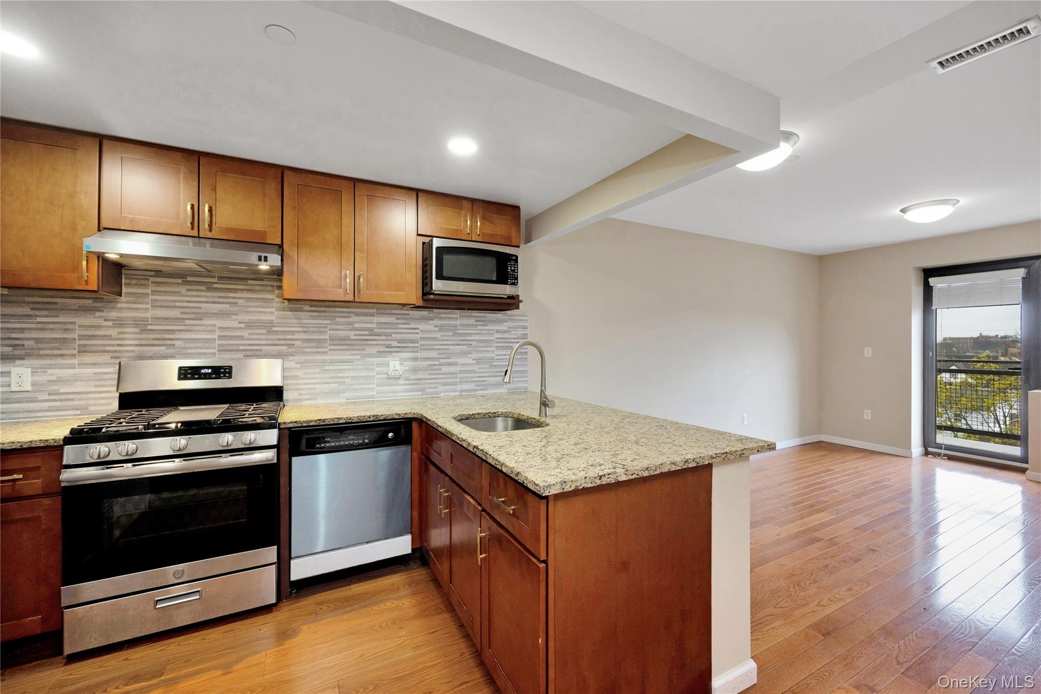 172-18 Jamaica Avenue, Unit 6C Queens, NY 11432 - Photo 3 of 23 a kitchen with stainless steel appliances granite countertop a stove a sink and a microwave