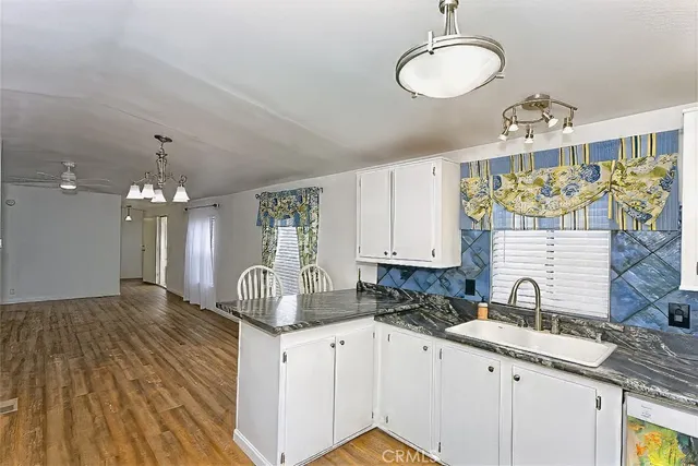 a kitchen with granite countertop a sink cabinets and wooden floor