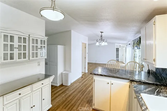 a kitchen with stainless steel appliances granite countertop a sink dishwasher and white cabinets with wooden floor