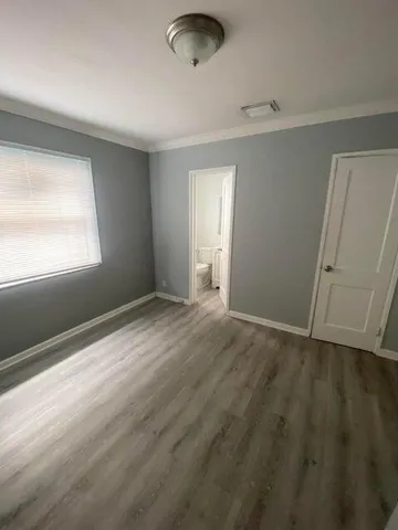 an empty room with window and hardwood floor