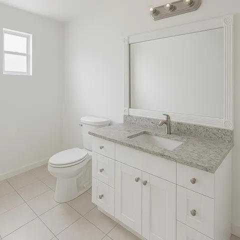 a bathroom with a granite countertop toilet sink and mirror