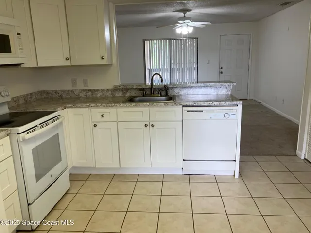 a kitchen with granite countertop white cabinets stainless steel appliances a sink and a counter top