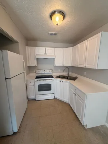 a kitchen with white cabinets and white appliances