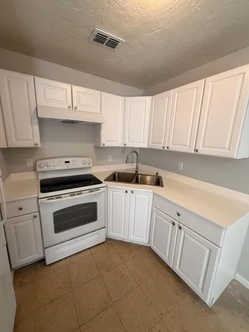 a kitchen with granite countertop white cabinets and white appliances
