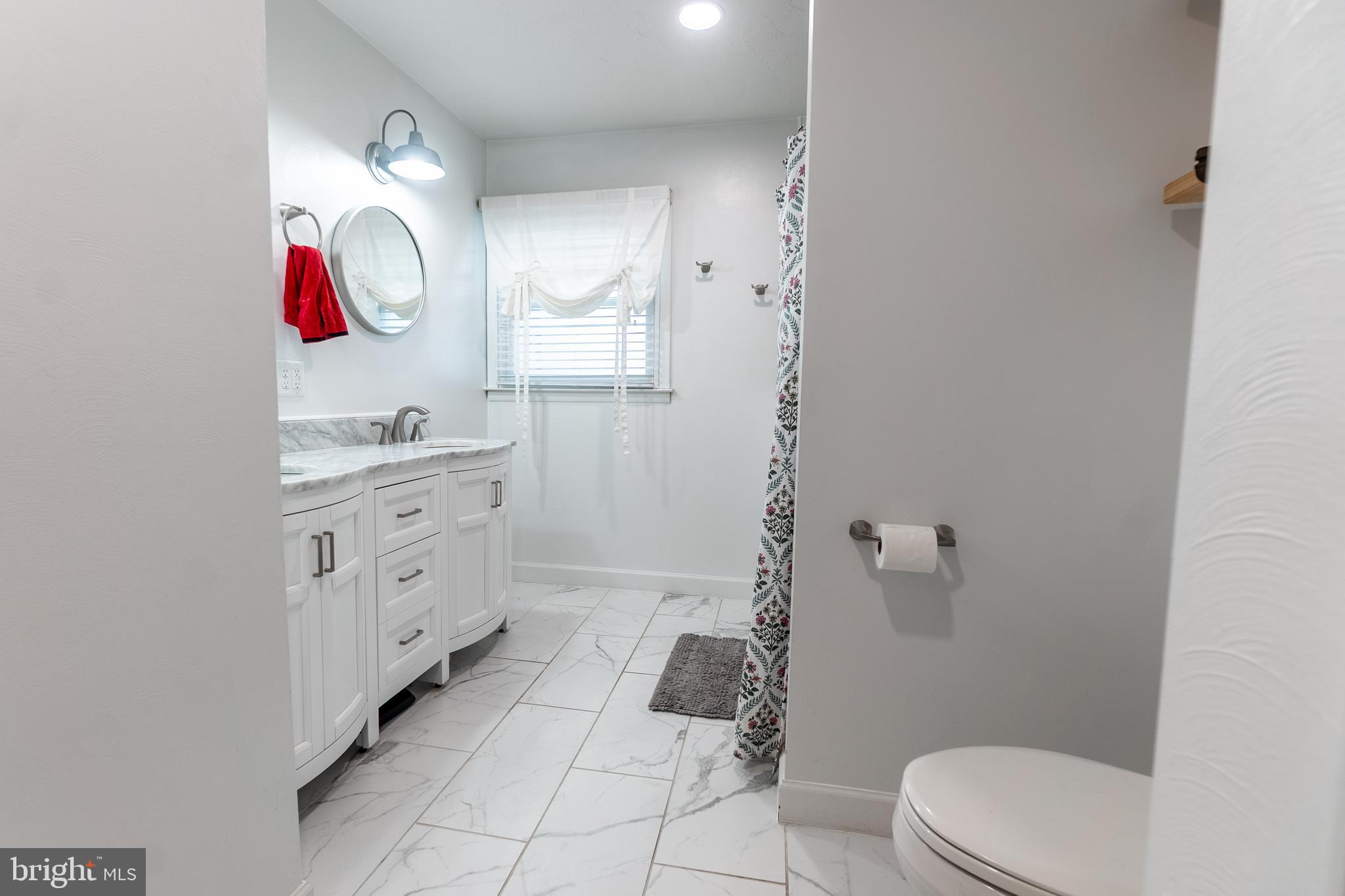 717 East Walnut Street Hanover, PA 17331 - Photo 9 of 21 a bathroom with a toilet a sink a mirror a vanity and a shower