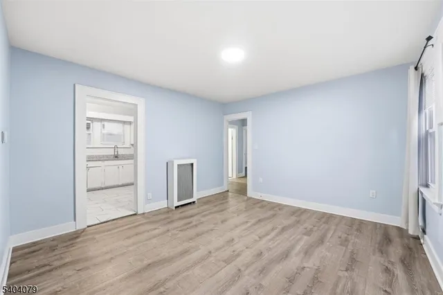 a view of an empty room with wooden floor and a bathroom