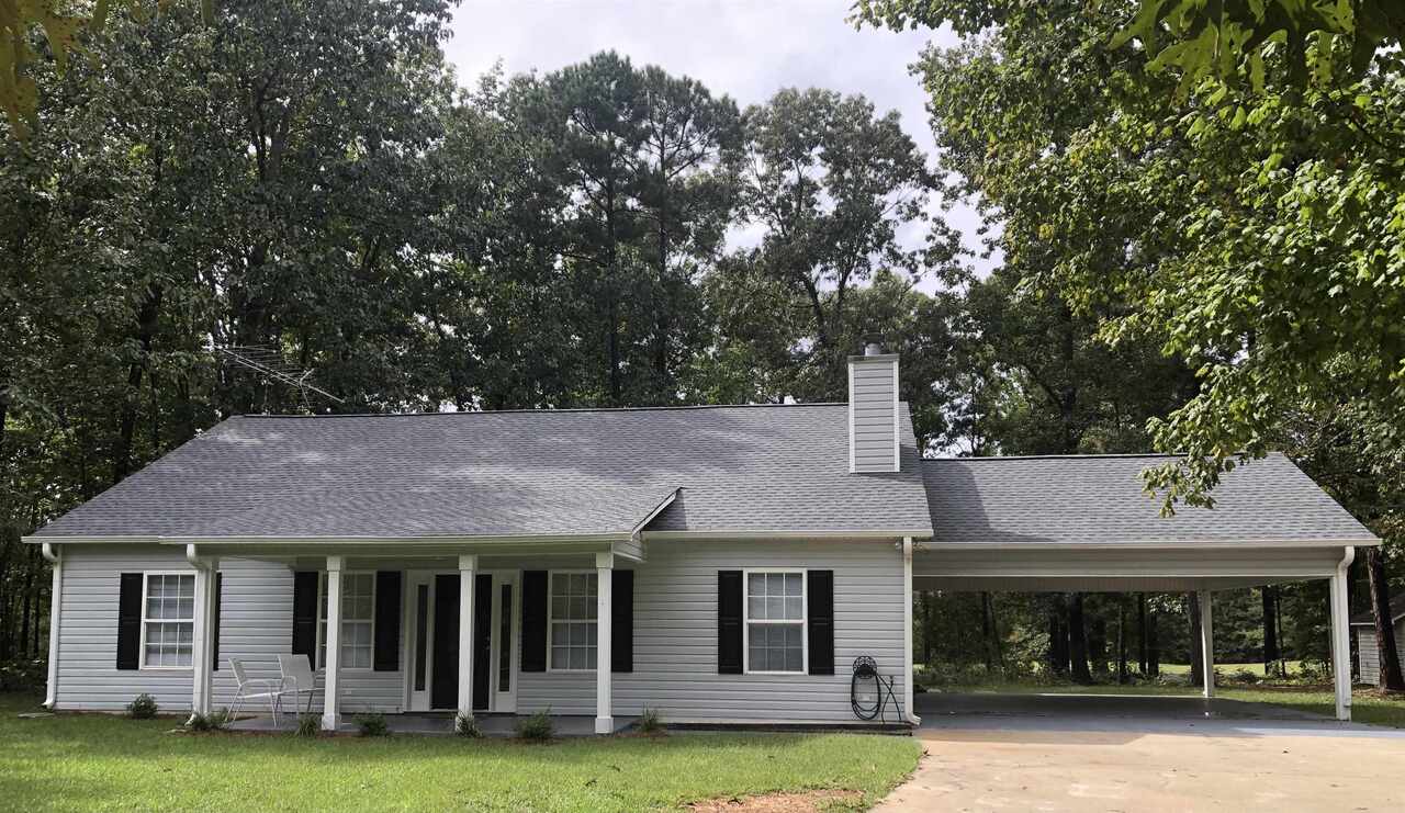 a view of a white house with a big yard and large trees
