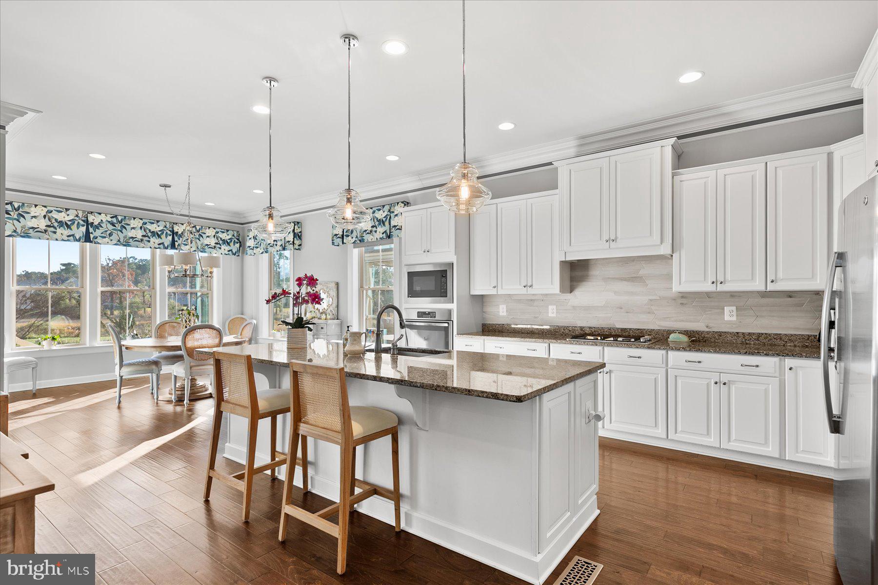 20822 Cormorant Way Ocean View, DE 19970 - Photo 15 of 91 a kitchen with stainless steel appliances granite countertop a stove top oven a sink a dining table and chairs with wooden floor
