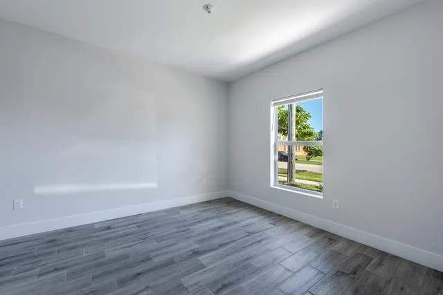 a view of an empty room with a window and wooden floor