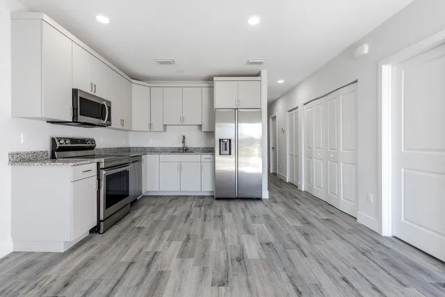 a kitchen with wooden floors white cabinets and stainless steel appliances