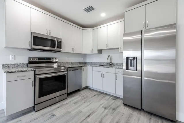 a kitchen with cabinets stainless steel appliances and wooden floor