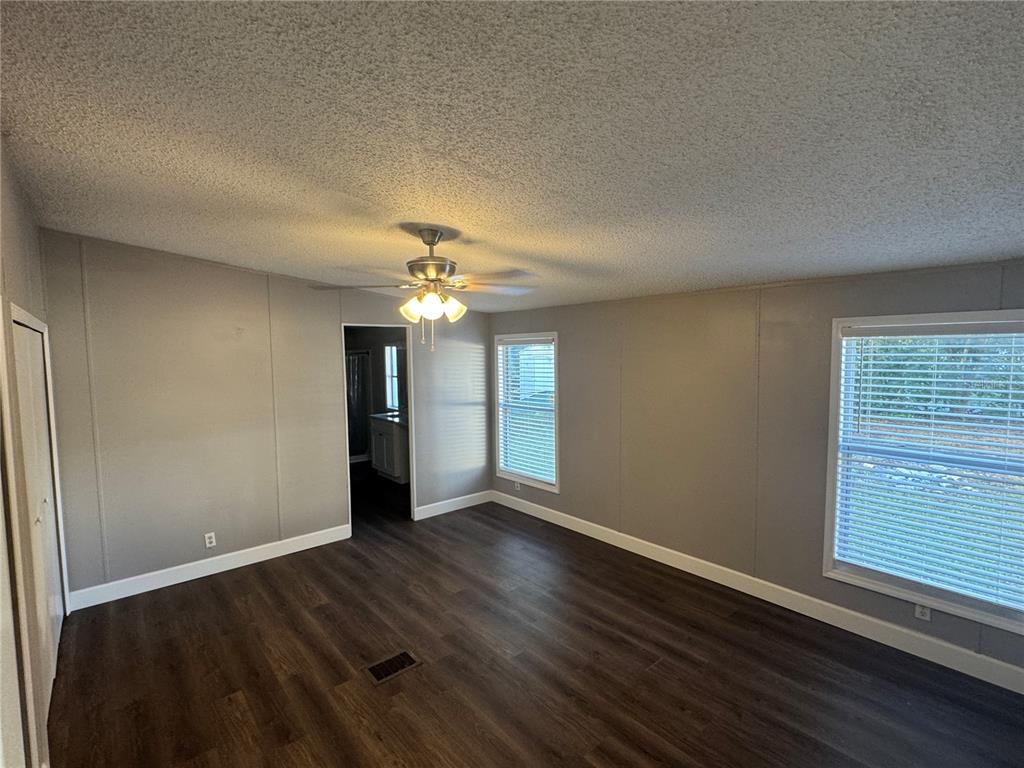 5254 Mt Olive Road Polk City, FL 33868 - Photo 12 of 19 an empty room with wooden floor chandelier fan and windows