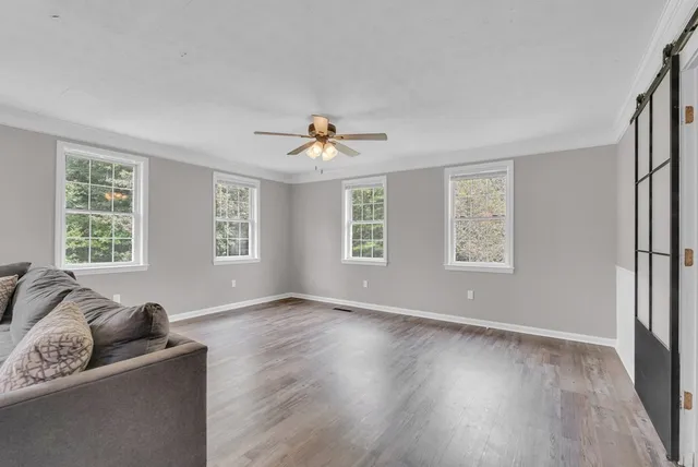 a view of an empty room with a window and wooden floor