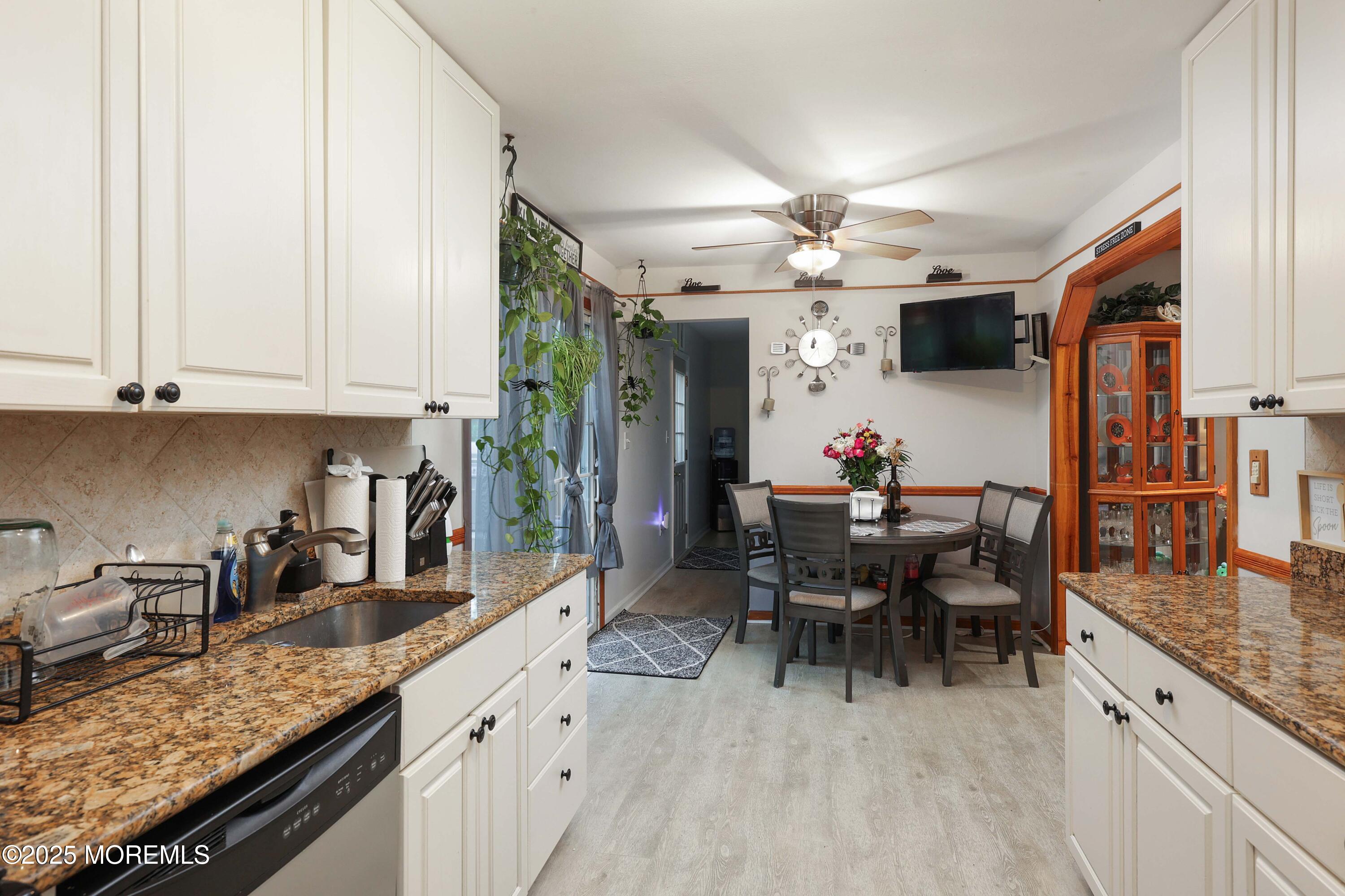 51 Alan Terrace Howell, NJ 07731 - Photo 9 of 32 a kitchen with stainless steel appliances granite countertop a sink dishwasher a stove a dining table and chairs with wooden floor