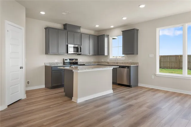 a kitchen with stainless steel appliances granite countertop a stove a sink and a microwave