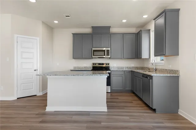 a kitchen with granite countertop a sink cabinets and stainless steel appliances