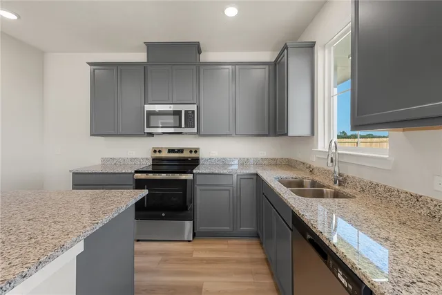 a kitchen with granite countertop a sink and steel appliances