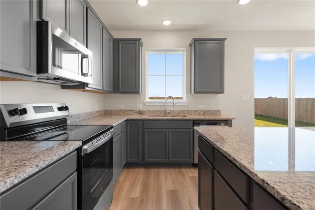 a kitchen with stainless steel appliances granite countertop a stove a sink and a microwave