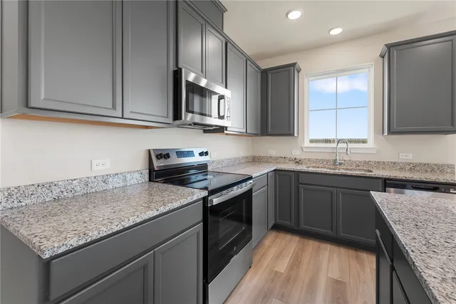 a kitchen with granite countertop cabinets stainless steel appliances and a counter space