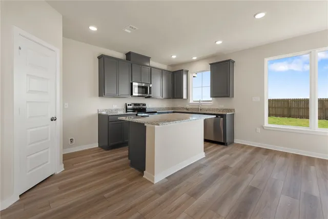 a kitchen with stainless steel appliances granite countertop a stove a sink and a refrigerator