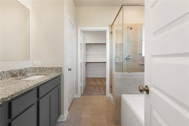 a bathroom with a granite countertop sink and mirror with bathtub