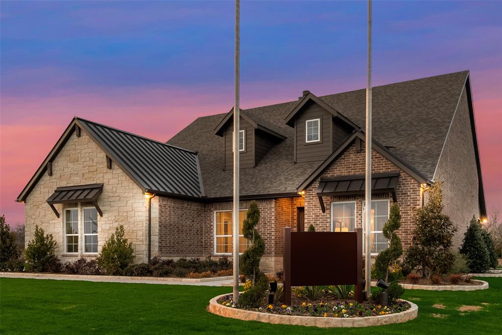 250 Brown Road Leonard, TX 75452 - Photo 5 of 29 Exterior featuring stone and brick siding, black metal roof accents, dormer windows, and a manicured lawn with decorative landscaping
