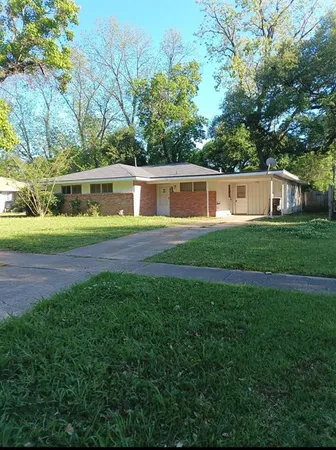 a front view of a house with garden and trees