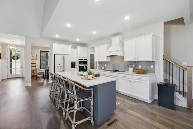 a kitchen with stainless steel appliances granite countertop a stove top oven a sink dishwasher and a refrigerator with wooden floor