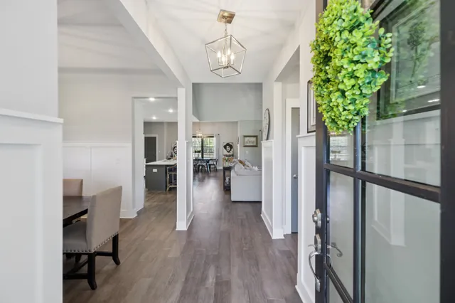 a view of a hallway with wooden floor windows and a chandelier