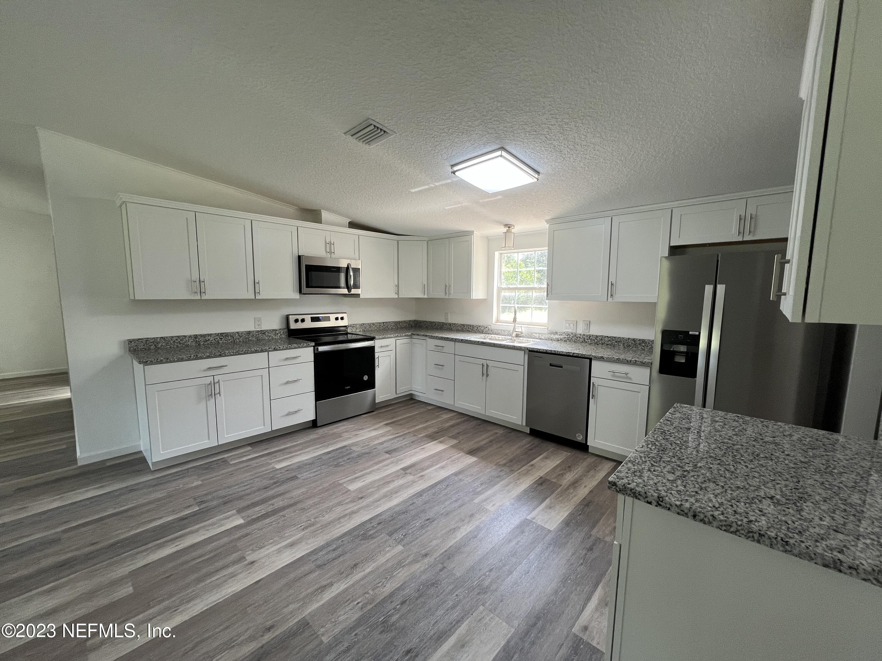 54291 Marlee Road Callahan, FL 32011 - Photo 5 of 7 a kitchen with granite countertop a sink stainless steel appliances and white cabinets