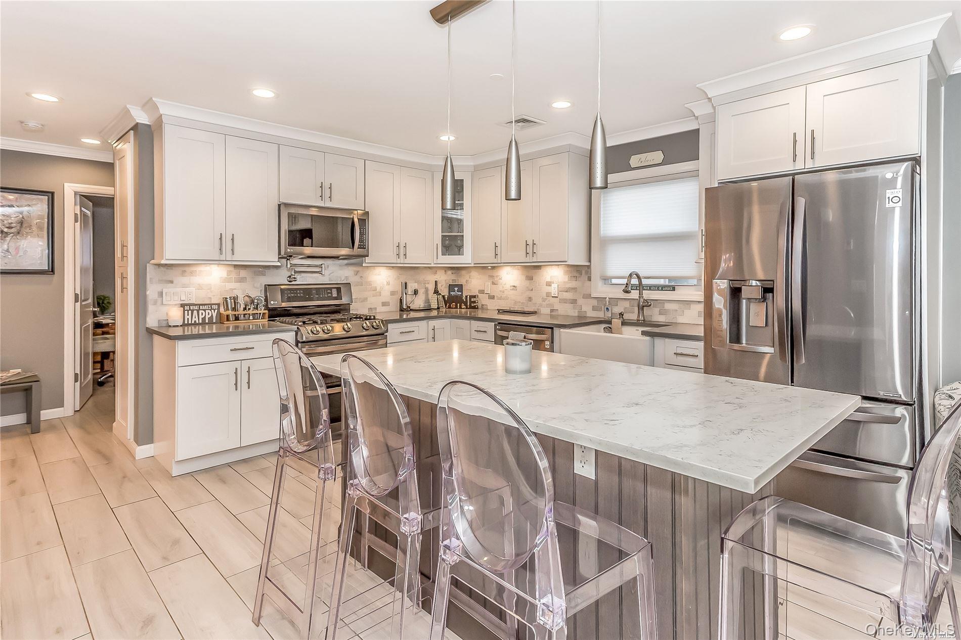 127 Maple Boulevard Long Beach, NY 11561 - Photo 6 of 22 a kitchen with stainless steel appliances granite countertop a kitchen island a stove a refrigerator a sink and white cabinets with wooden floor