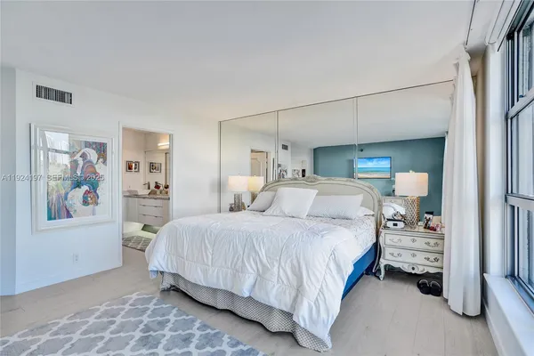 a bedroom with a large bed and a painting on the wall