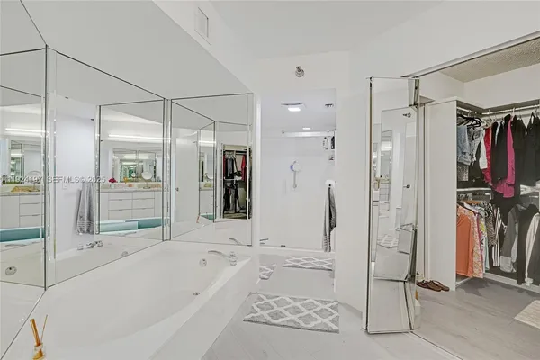 a bathroom with a tub shower and mirror