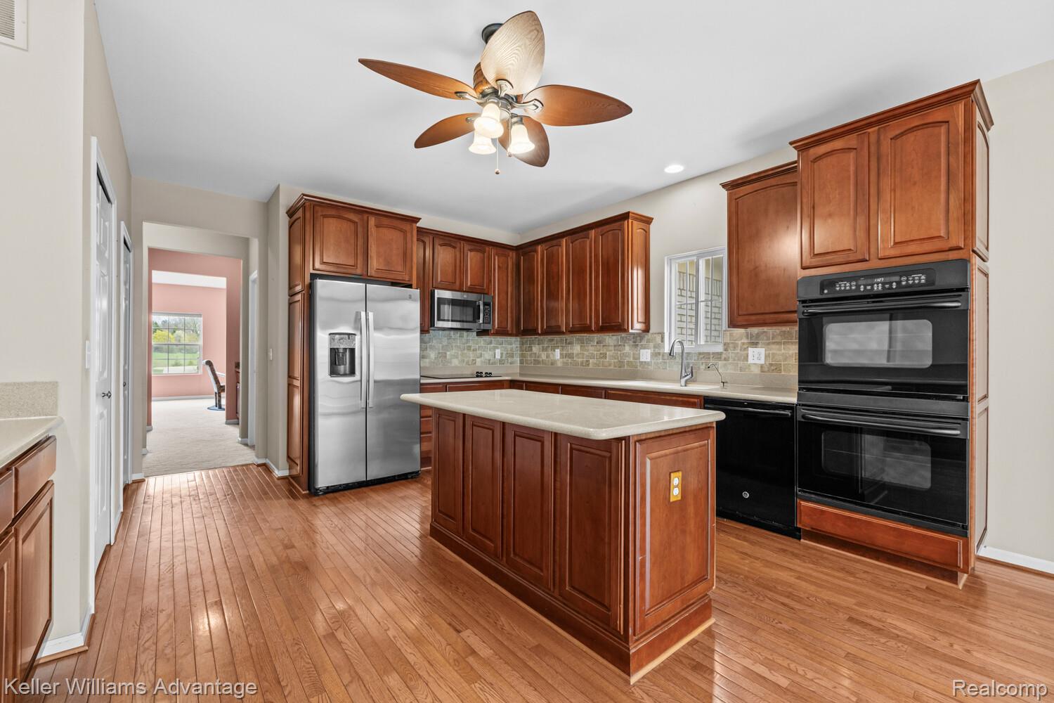 4100 Norwich Court Rochester, MI 48306 - Photo 15 of 72 Kitchen featuring black appliances, ceiling fan, tasteful backsplash, light wood-style flooring, and a center island