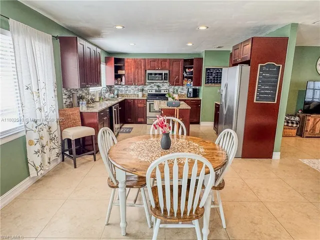 a dining room with furniture a kitchen island a refrigerator and a stove